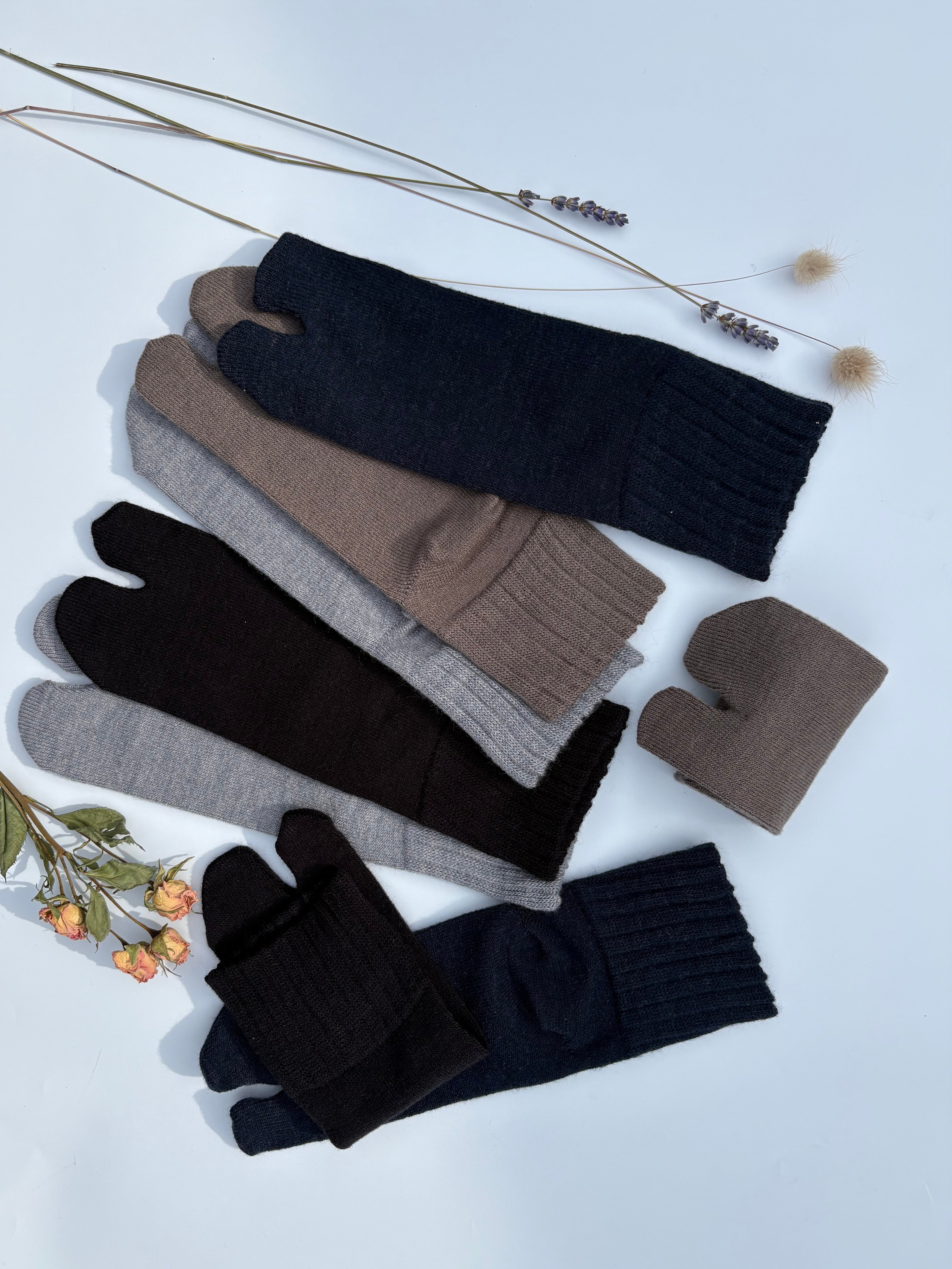Flat lay of ankle length tabi split-toe socks in black, dark navy, brown, taupe, and grey — warm knit Japanese tabi socks styled with dried lavender and roses wool blend