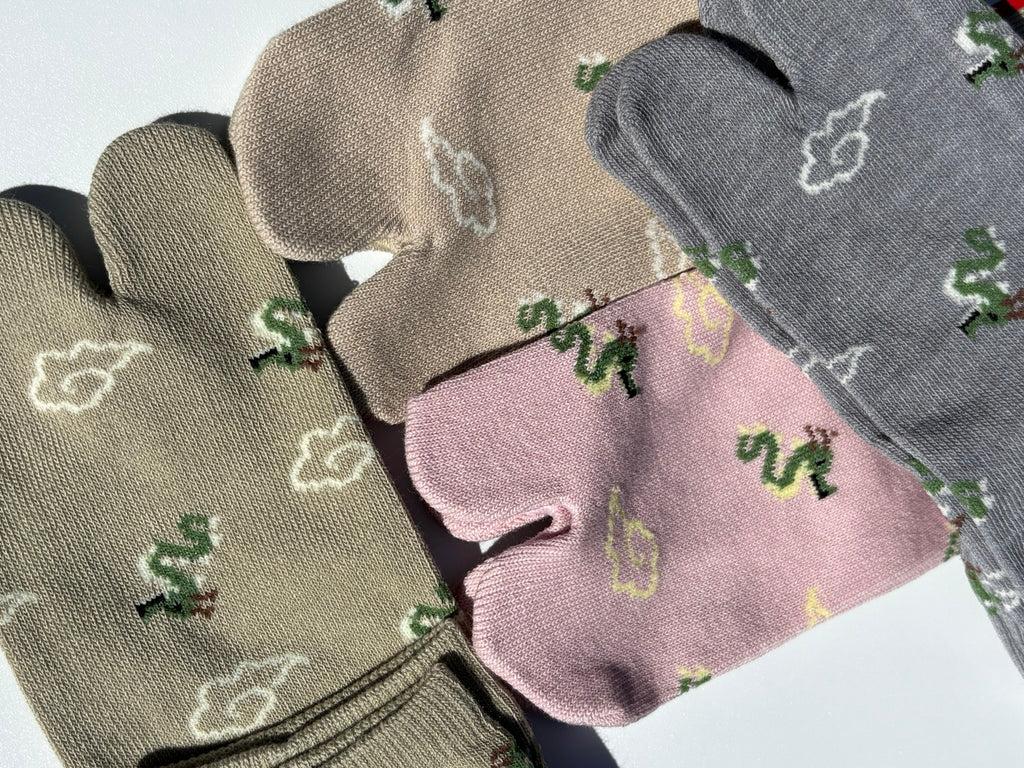 close up of four pairs of dragon and clouds print tabi socks made in japan premium cotton quality lay flat on white background in sage taupe grey and pink