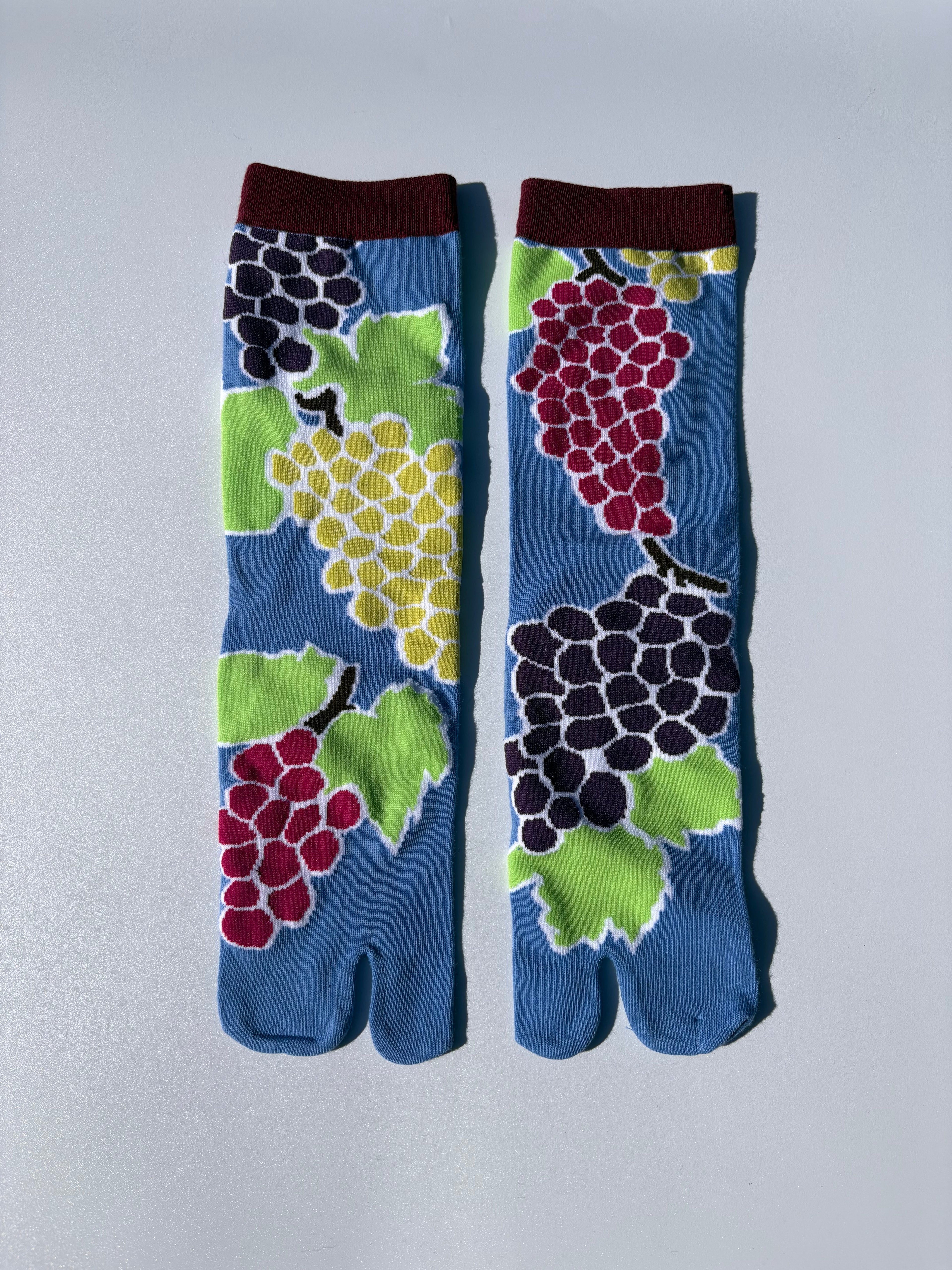 Pair of blue tabi socks with fruit pattern on a light blue background
