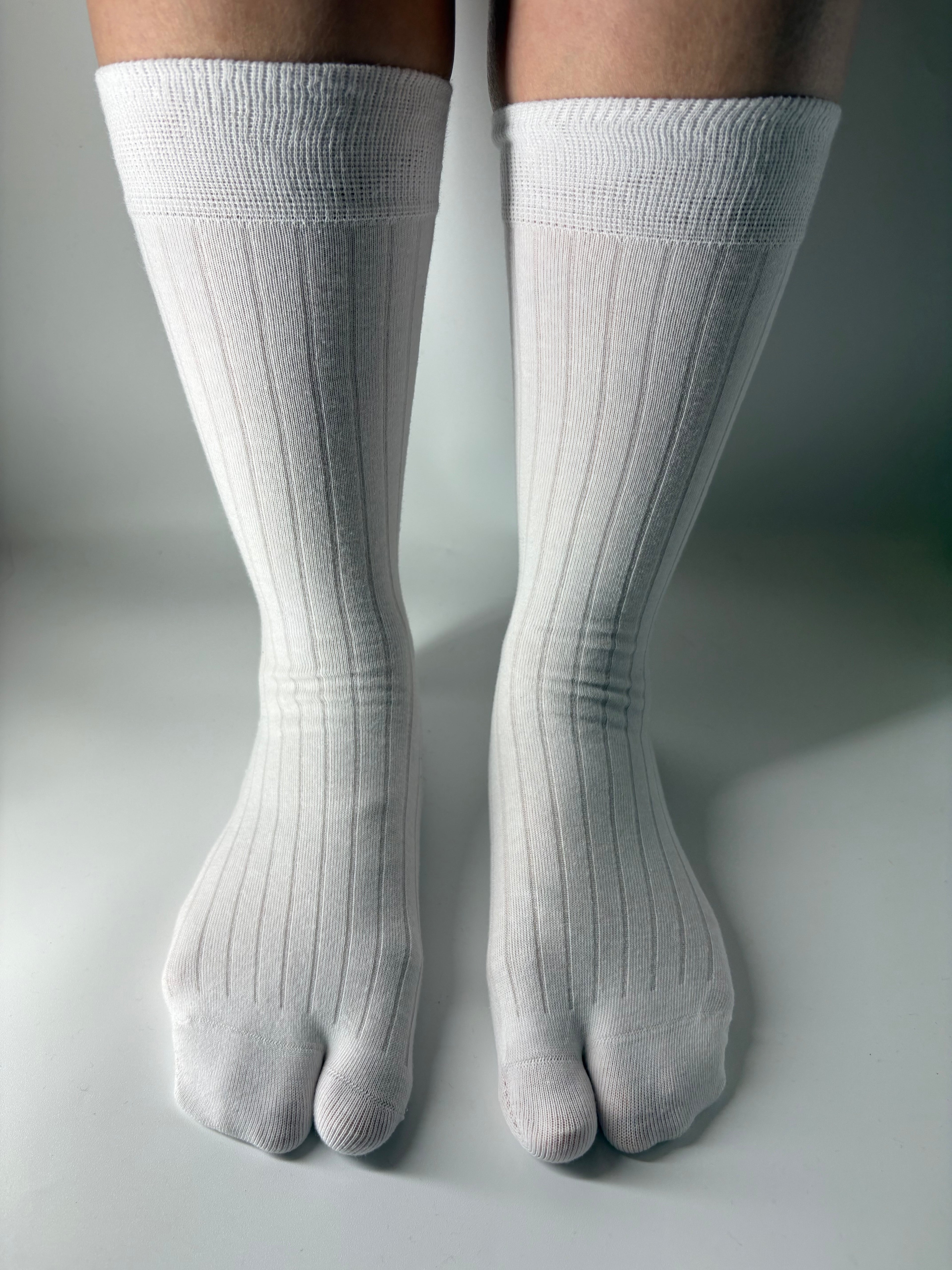 White crew split toe socks on a neutral background