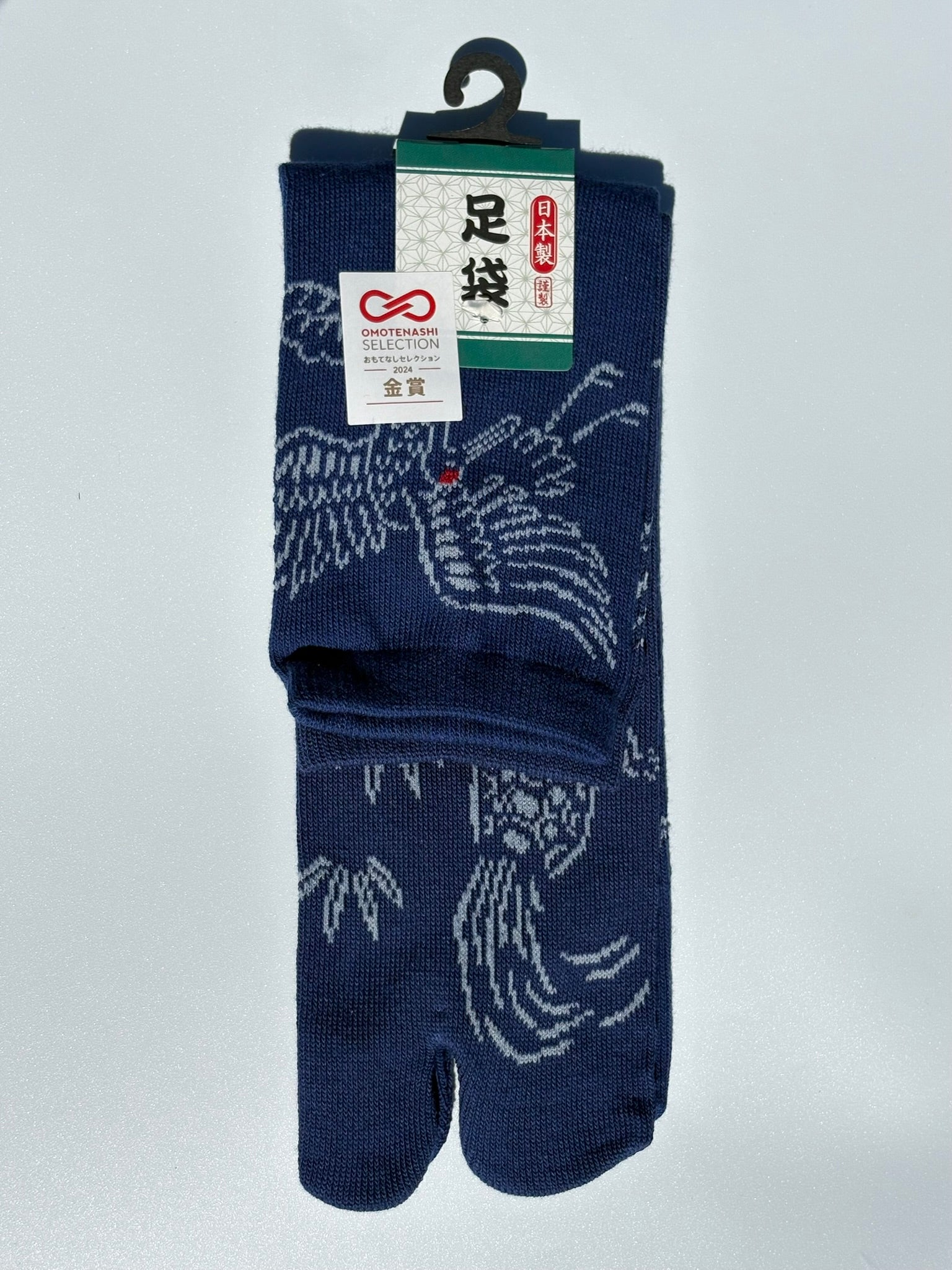 Pair of navy blue tabi socks with white patterns on a light gray background