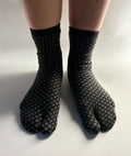 Black tabi split-toe socks with grey diamond (hishi) pattern worn on feet — Japanese hishi pattern tabi socks styled on bare legs