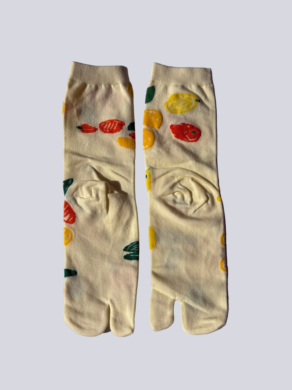 Pair of yellow citrus lemon print tabi socks illustration on a light gray background made of cotton 