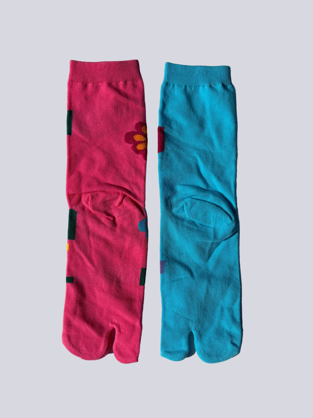 Back of Colorful tabi socks with floral bold pop art neon pink and blue floral patterns on a light gray background