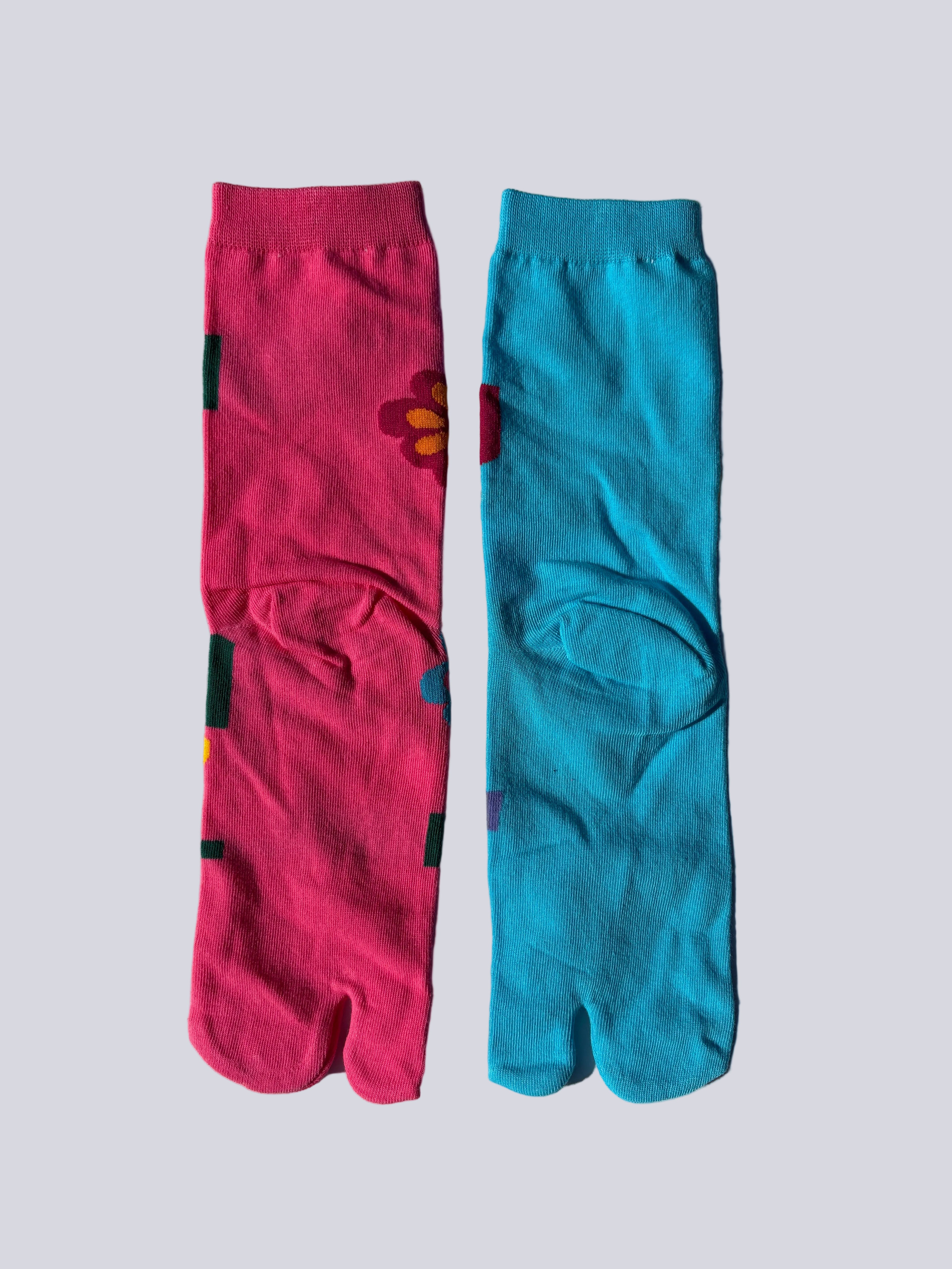 Back of Colorful tabi socks with floral bold pop art neon pink and blue floral patterns on a light gray background