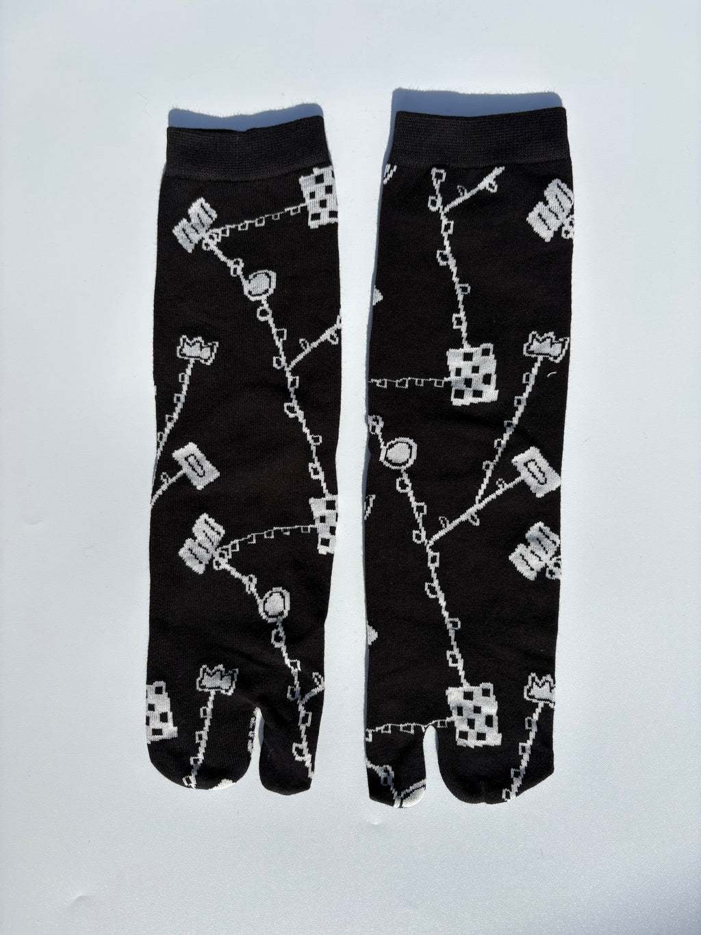 Black japanese split toe tabi socks with white pattern on a light gray background
