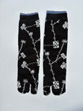 Black japanese split toe tabi socks with white pattern on a light gray background