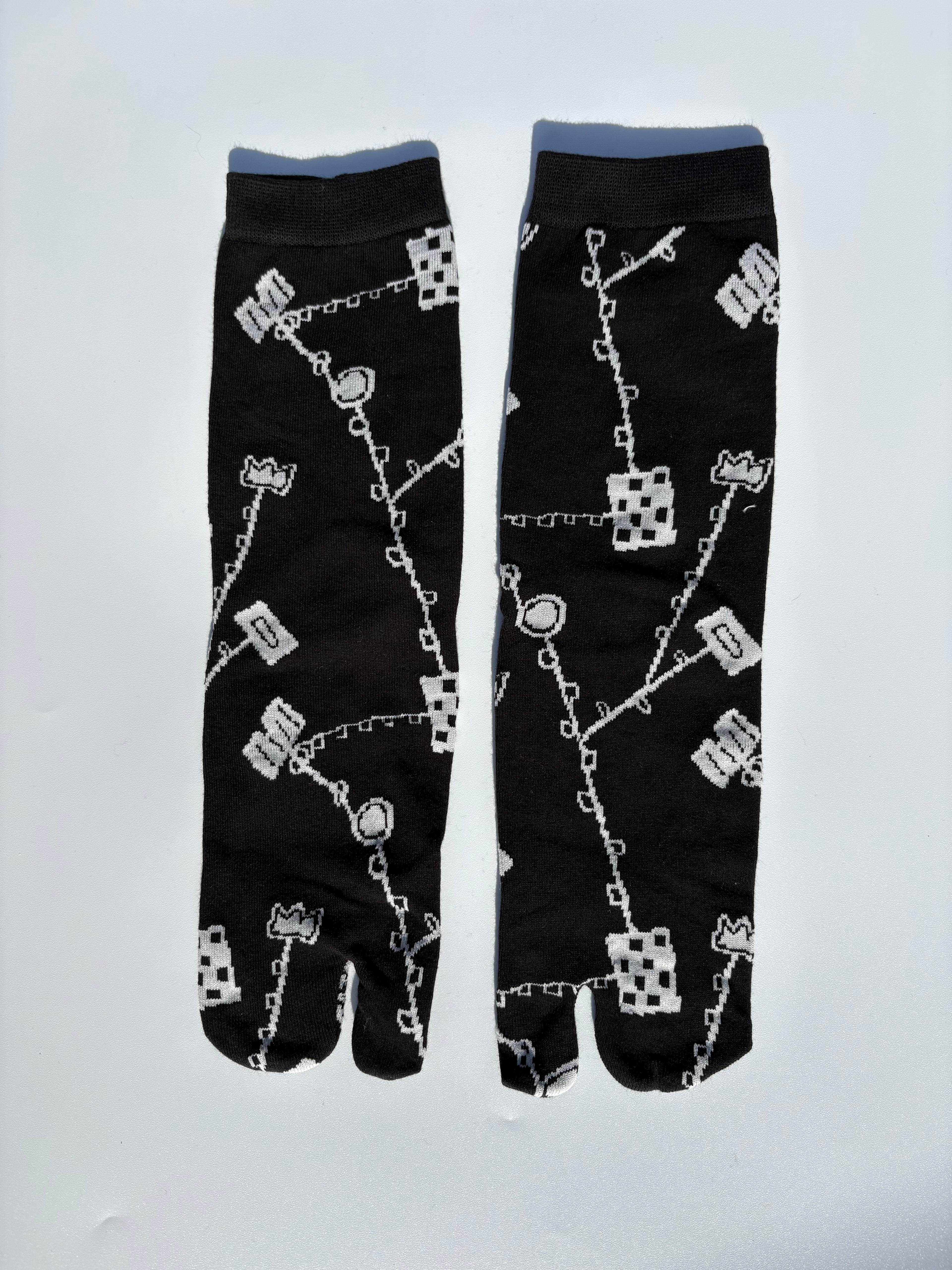 Black japanese split toe tabi socks with white pattern on a light gray background