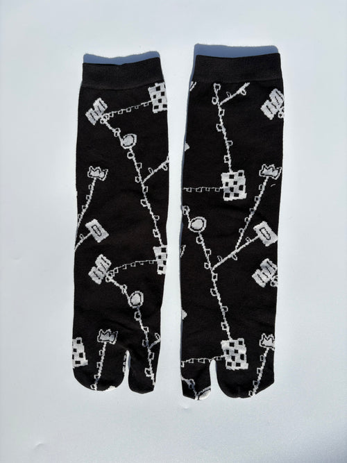 Black japanese split toe tabi socks with white pattern on a light gray background