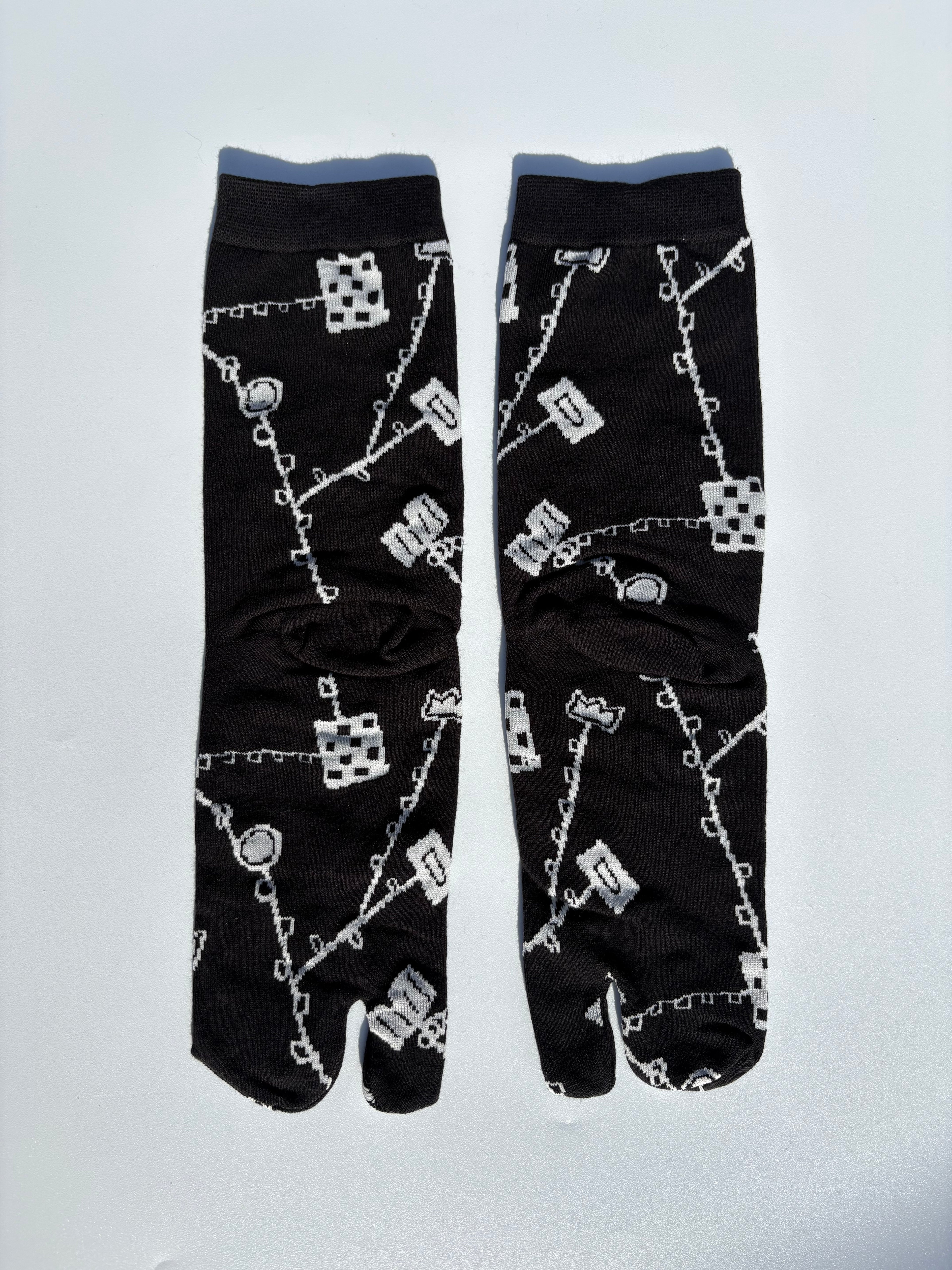 Black japanese split toe tabi socks with white pattern on a light gray background