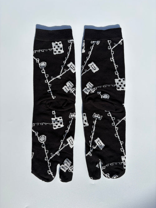 Black japanese split toe tabi socks with white pattern on a light gray background