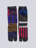 Two pairs of patterned tabi socks with playful mix of colour block panels, polka dots, and bold stripes on a light gray background