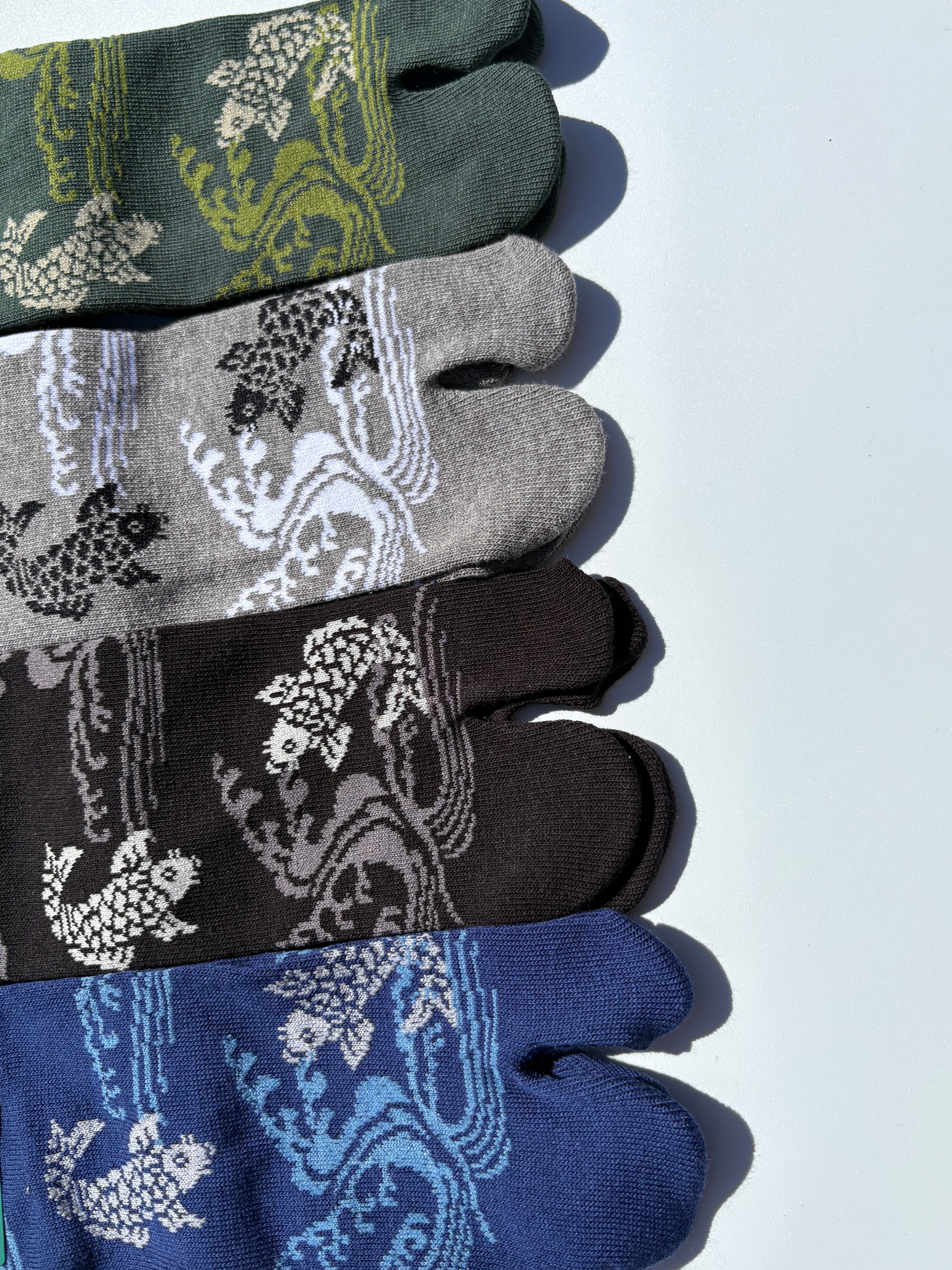 close up of four pairs of patterned koi fish traditional japanese tabi socks socks on a white background