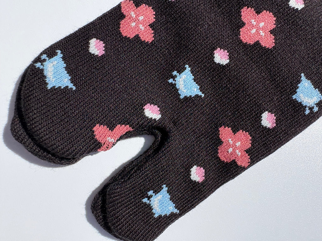 close up of black bird print tabi socks - japanese split toe design made of cotton - flat lay on white background made in japan