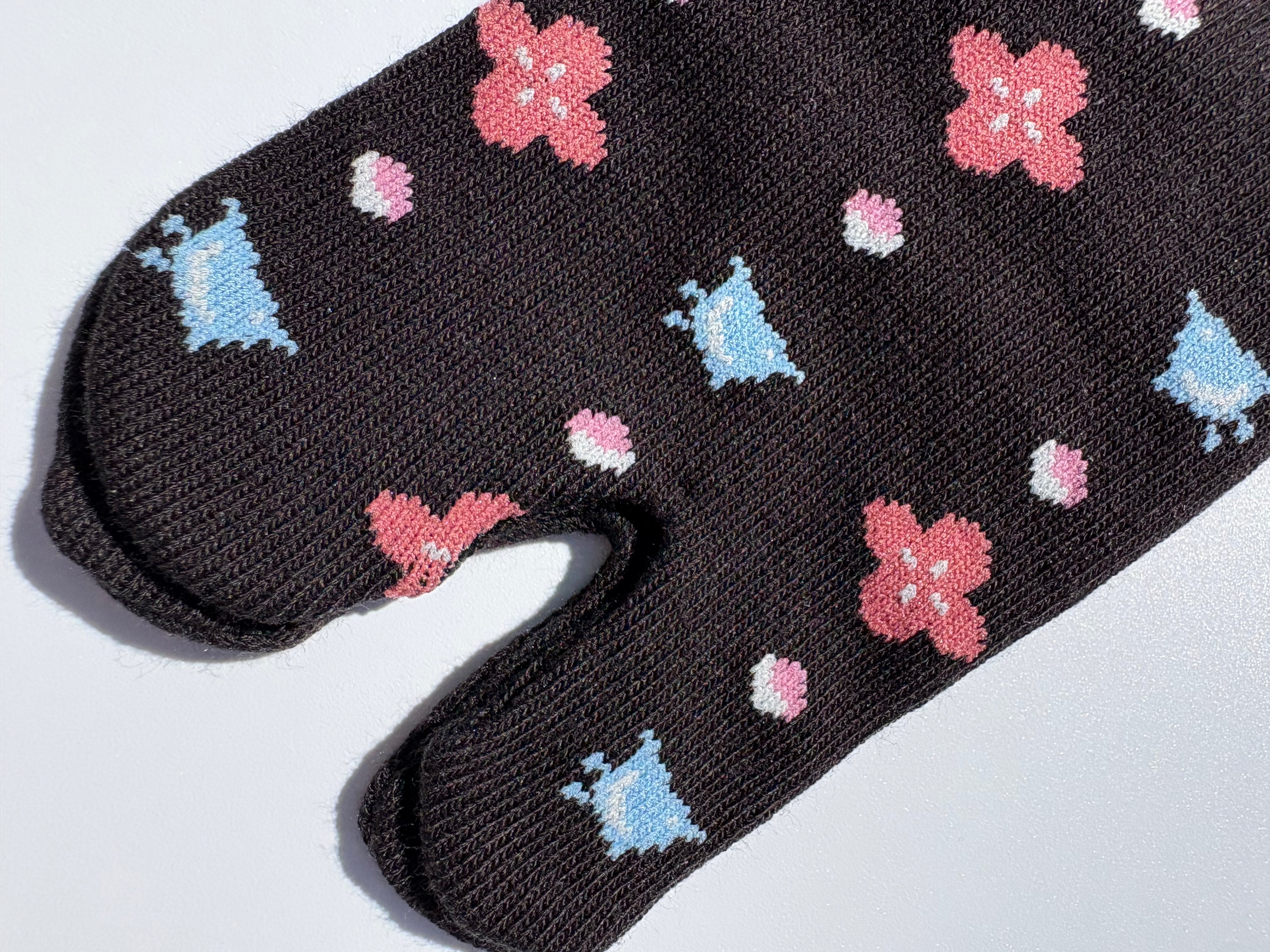 close up of black bird print tabi socks - japanese split toe design made of cotton - flat lay on white background made in japan