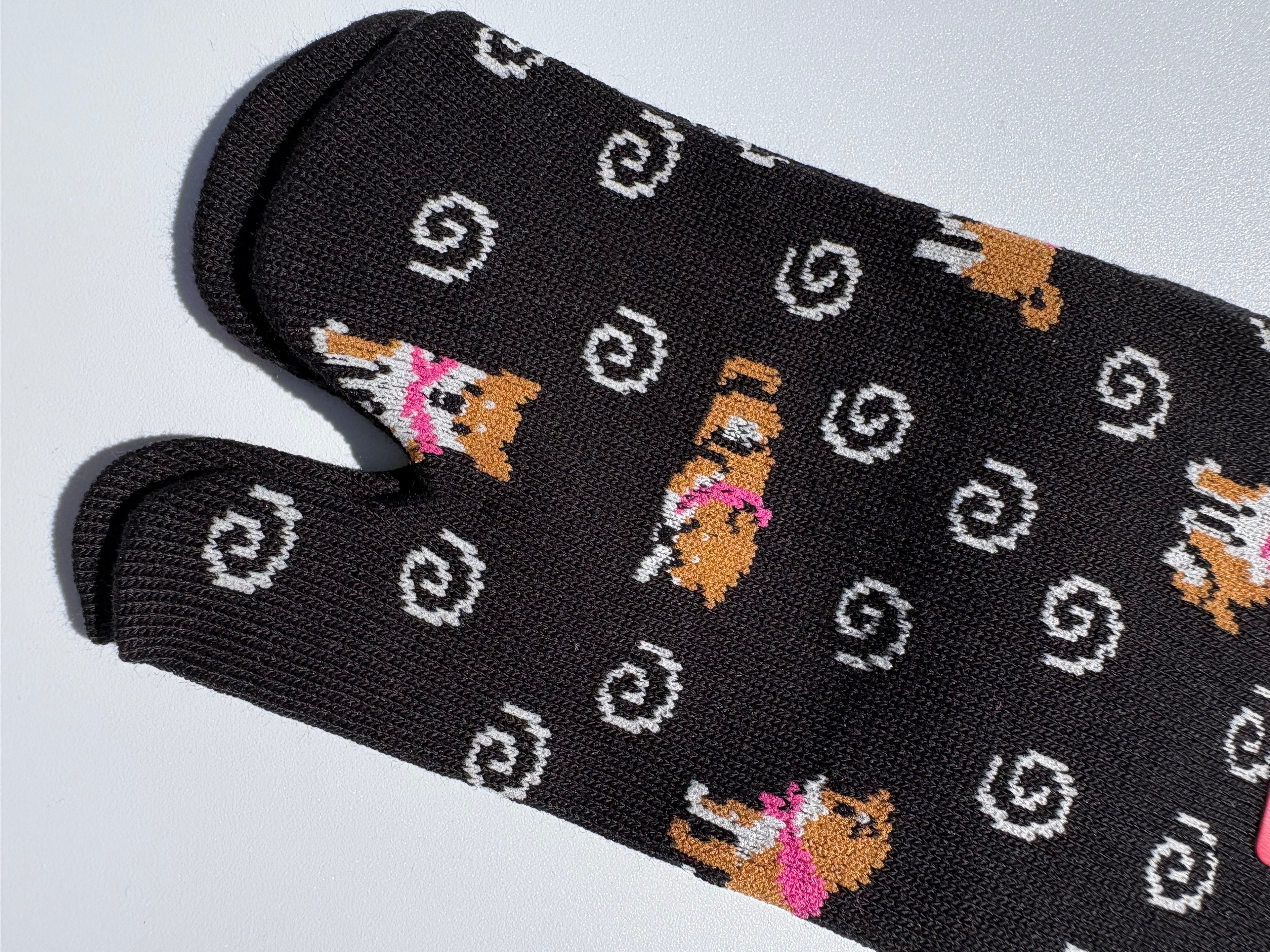 close up of black pair of shiba inu dog print tabi socks on a white background