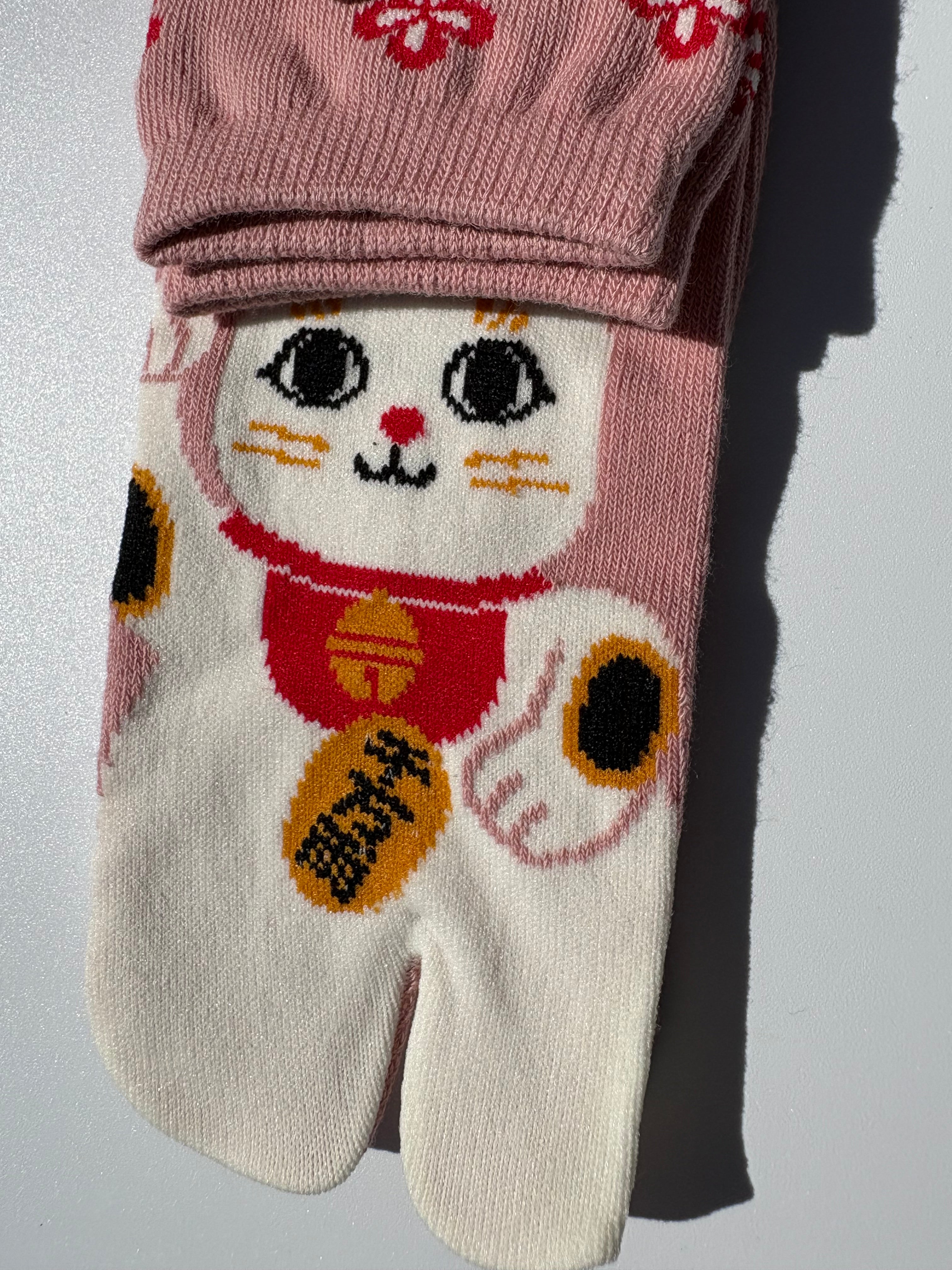 close up of Pink tabi split-toe socks with maneki-neko lucky cat print and red floral pattern — Japanese-made novelty lucky cat tabi socks (足袋)
