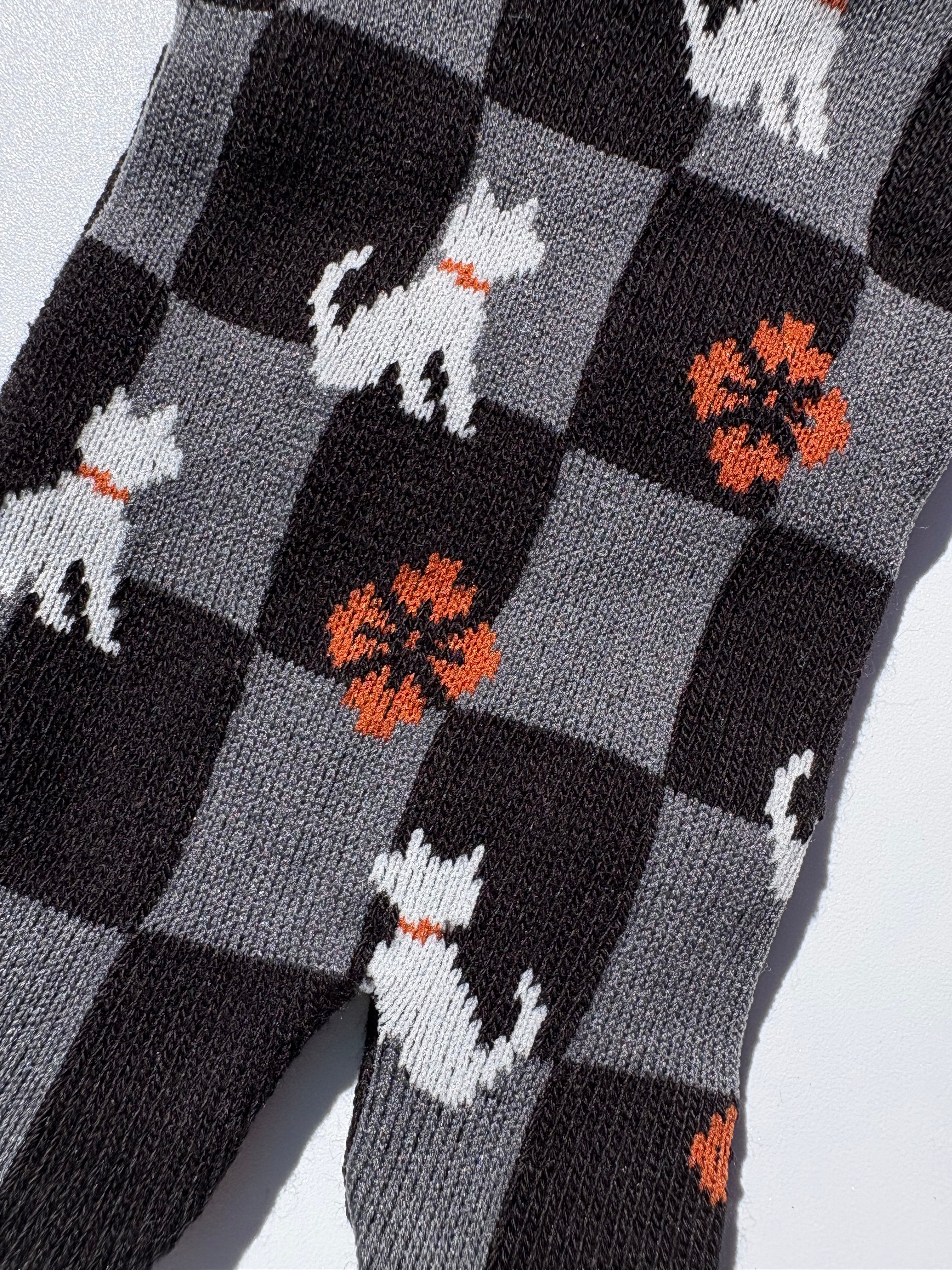 close up of checkered print tabi socks featuring orange blossom and white dog wearing a red collar