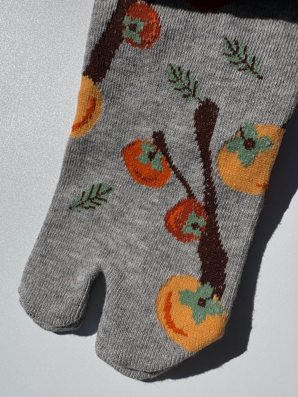 Close up of Grey tabi split-toe socks with Japanese persimmon (kaki) fruit and branch print — novelty Japanese-made tabi socks (足袋)