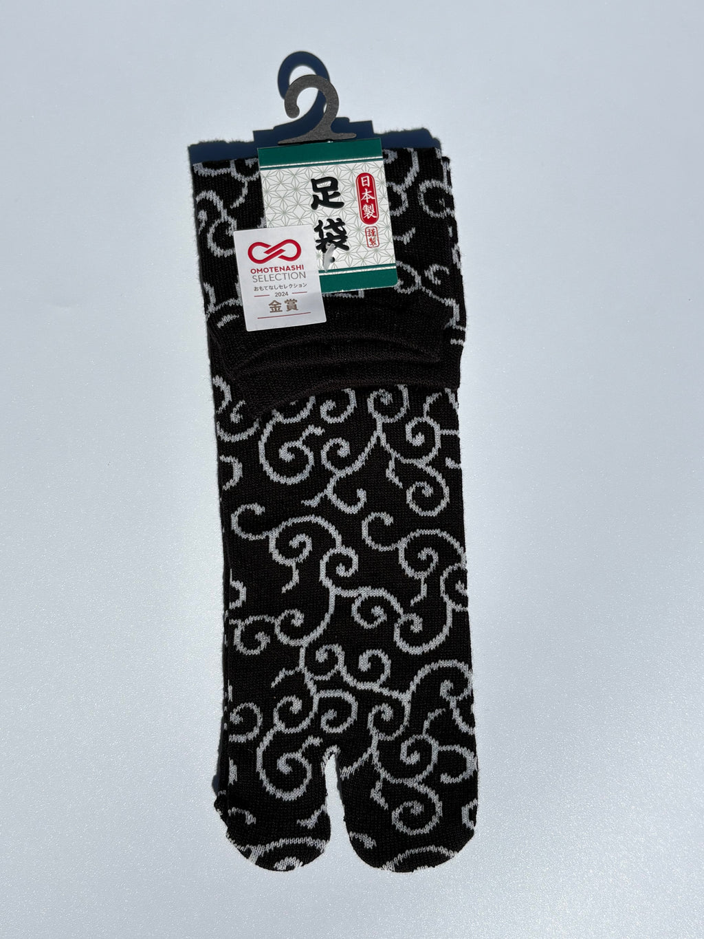 black tabi split-toe socks with white karakusa arabesque scroll pattern — Omotenashi Selection Gold Award 2024 Japanese-made tabi socks (足袋)