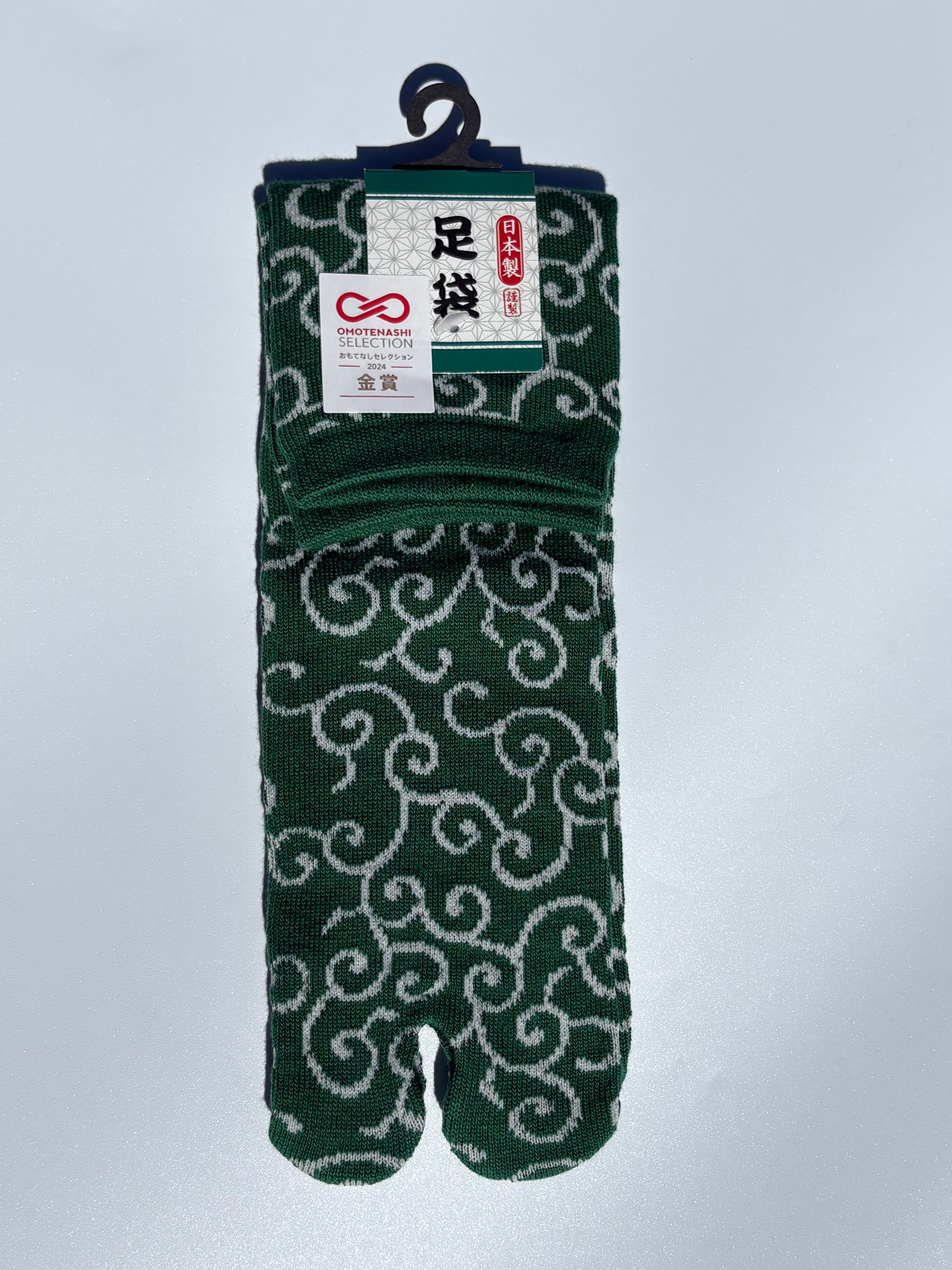 green tabi split-toe socks with white karakusa arabesque scroll pattern — Omotenashi Selection Gold Award 2024 Japanese-made tabi socks (足袋)