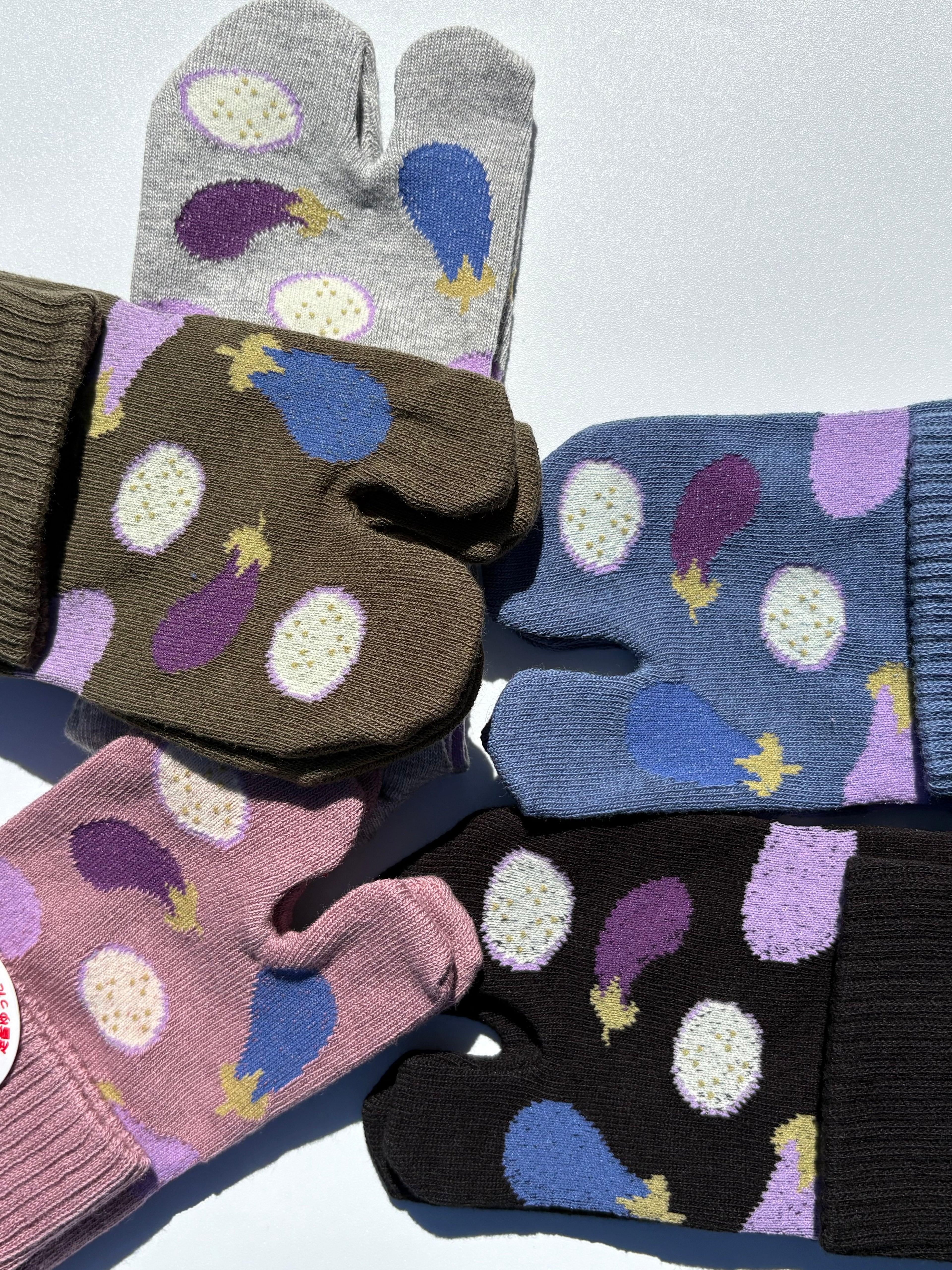 close up of five pairs of Japanese tabi split-toe socks with aubergine and turnip vegetable print in blue, olive, black, and mauve — soft elastic relaxed-fit tabi socks made in Japan