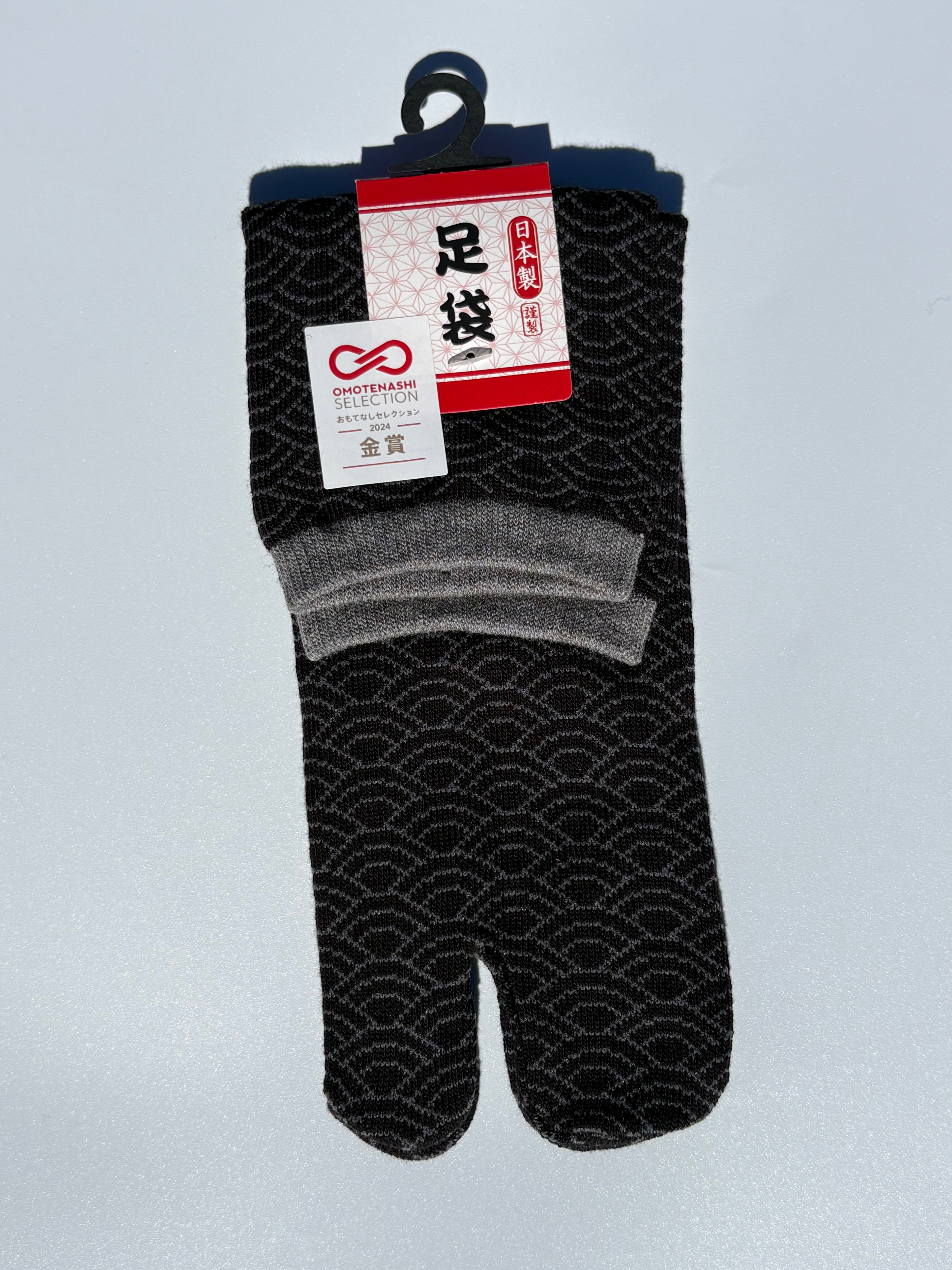 Pair of black seigeiha print tabi socks in grey accent cuff with a pattern on a light gray background