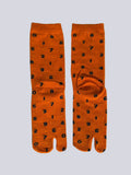 Pair of orange tabi socks with black number pattern on a white background