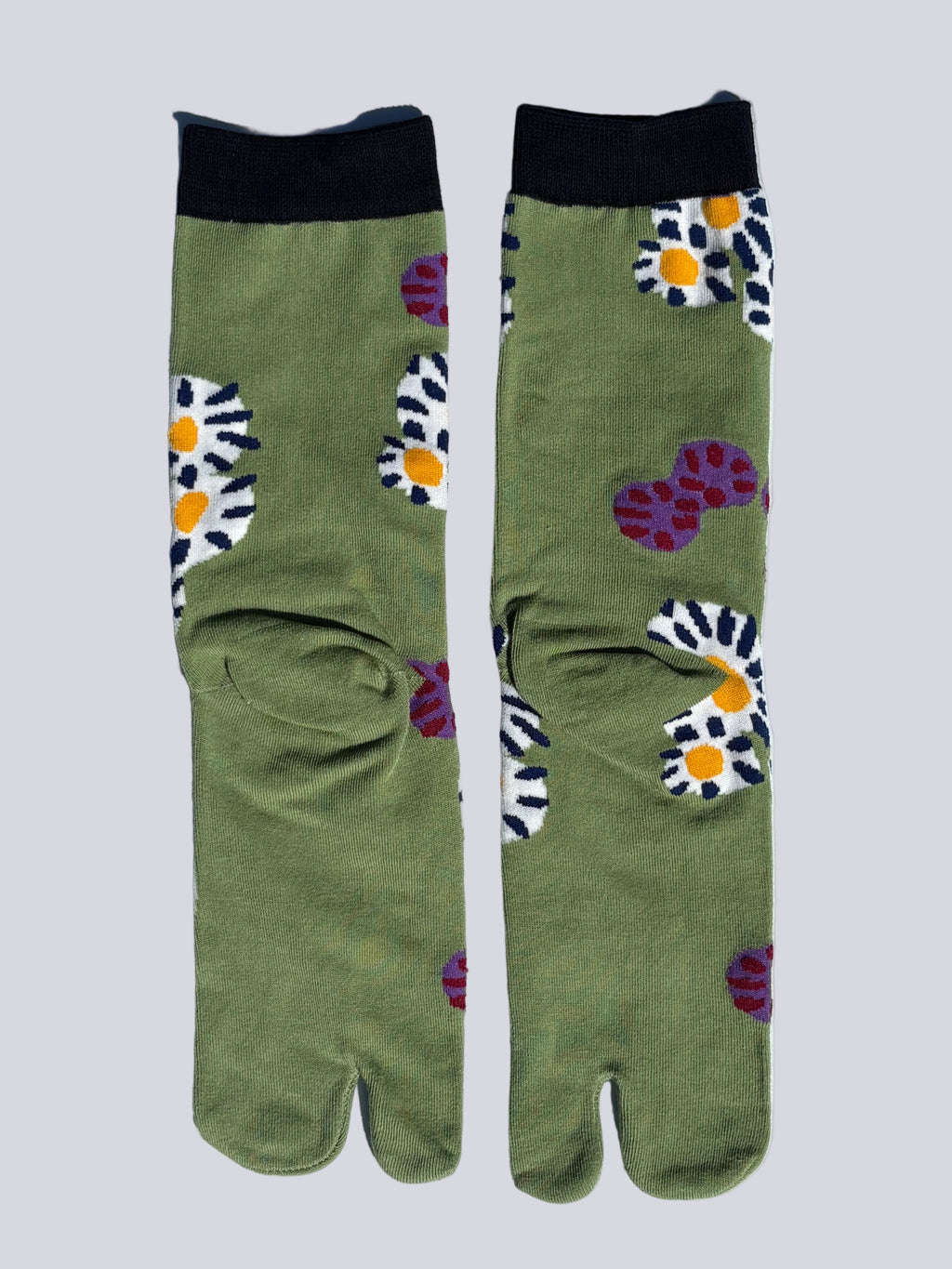 Pair of green tabi socks with floral patterns on a light gray background