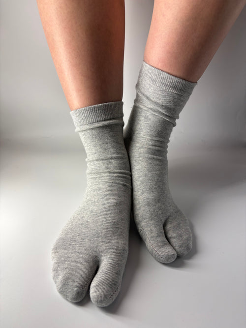 Gray tabi socks worn on a neutral background