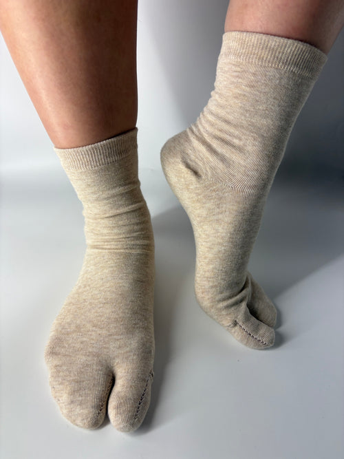 Beige tabi socks worn on a plain background
