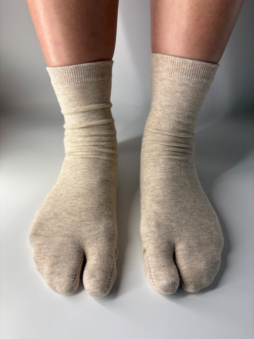 Beige tabi socks worn on a neutral background