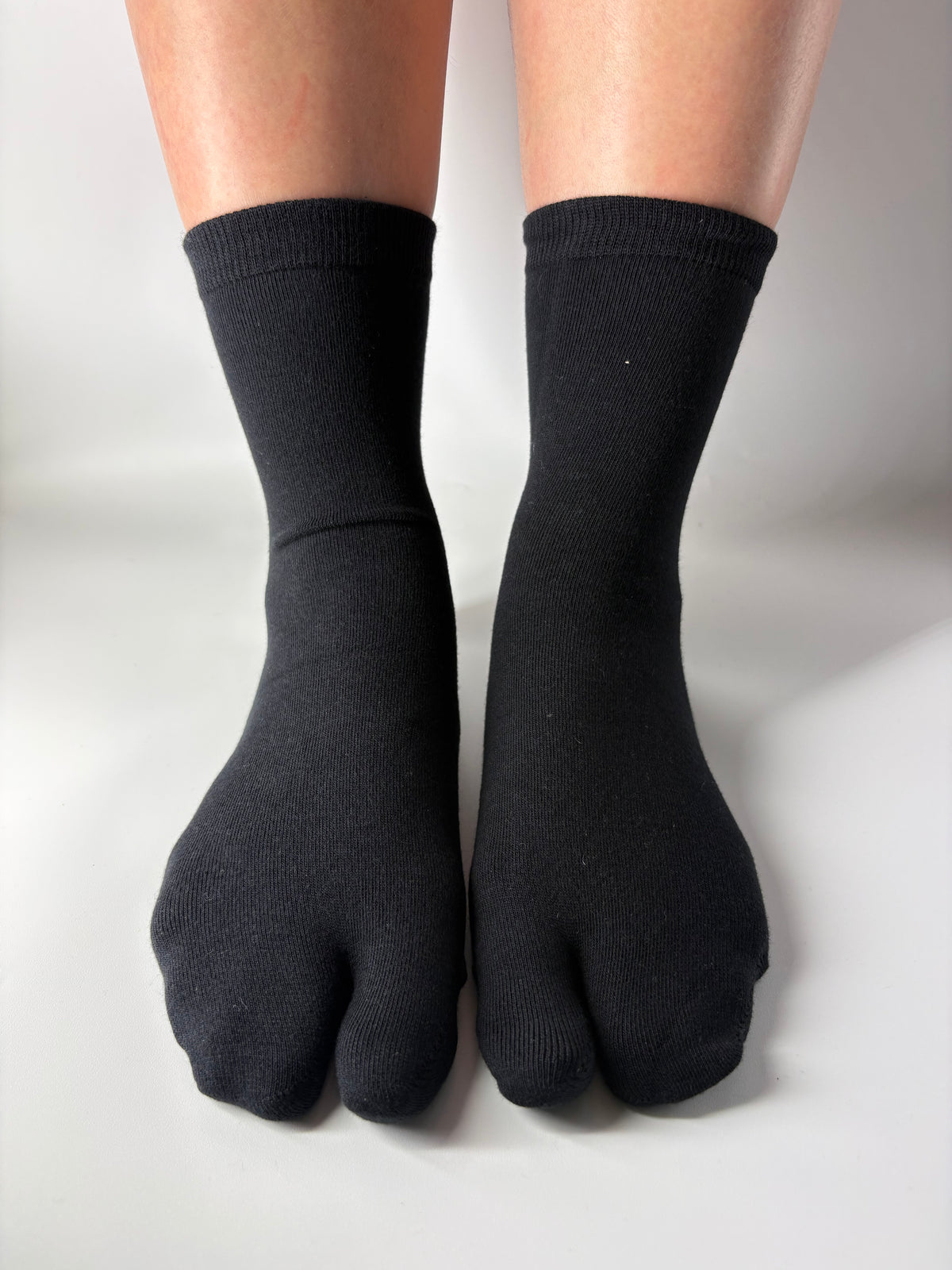 Black toe-separated socks worn on a white background