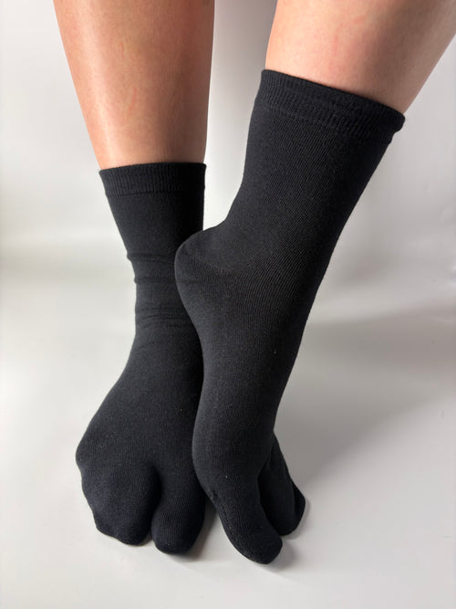 Black toe-separated socks worn on a white background