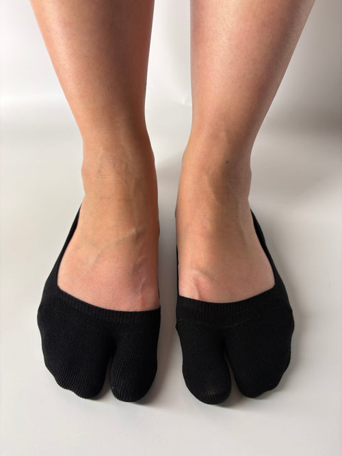 Black invisible seamless split toe socks worn by a person on a white background