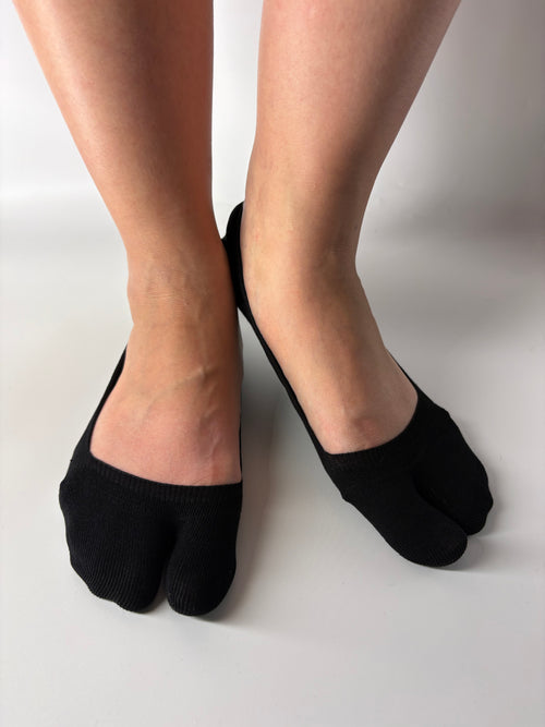 Black invisible seamless split toe socks worn by a person on a white background