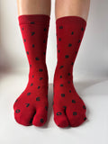 Red socks with black patterns worn by a person on a white background