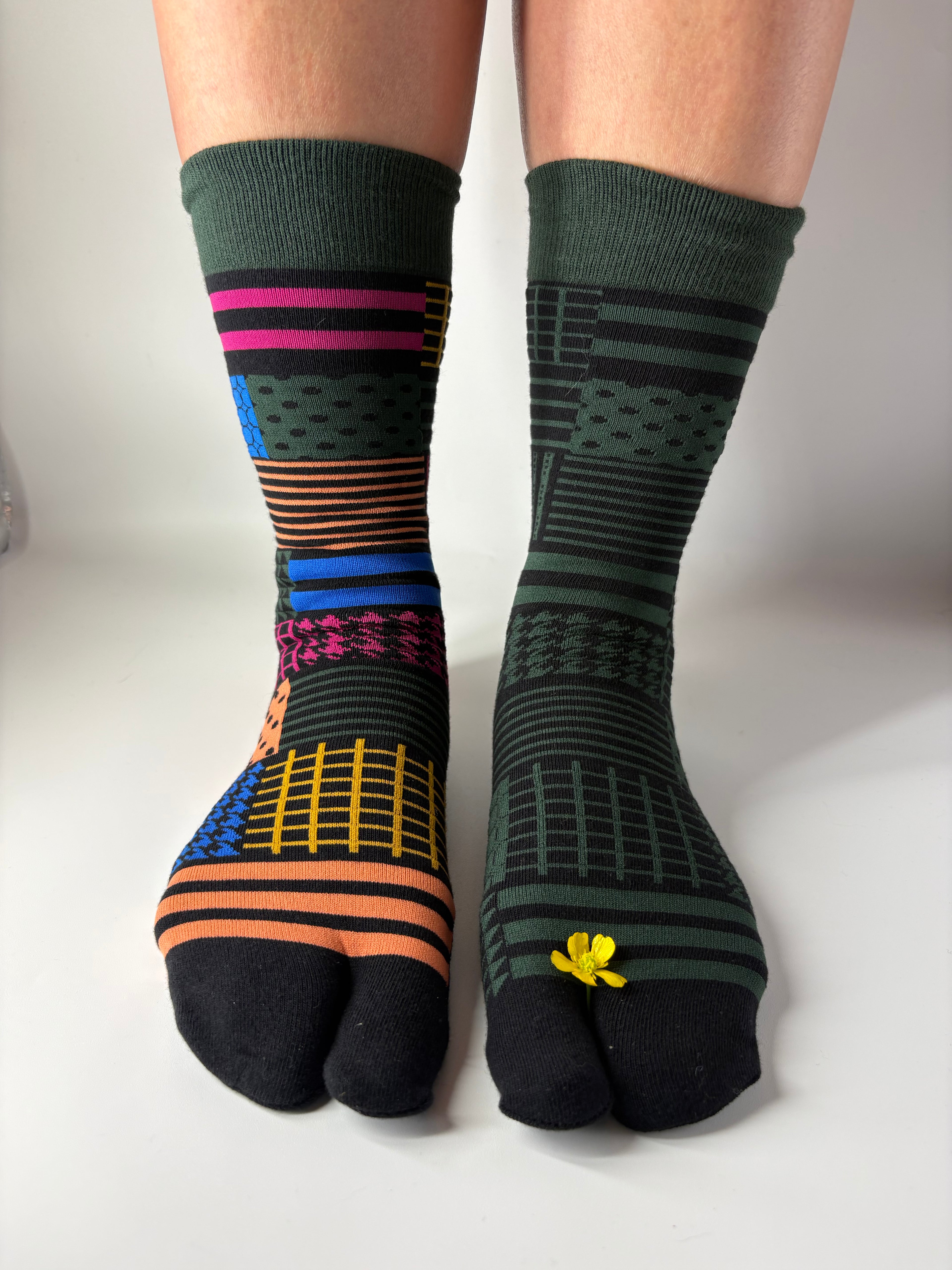 Colorful asymmetric geometric patterned socks on a plain background