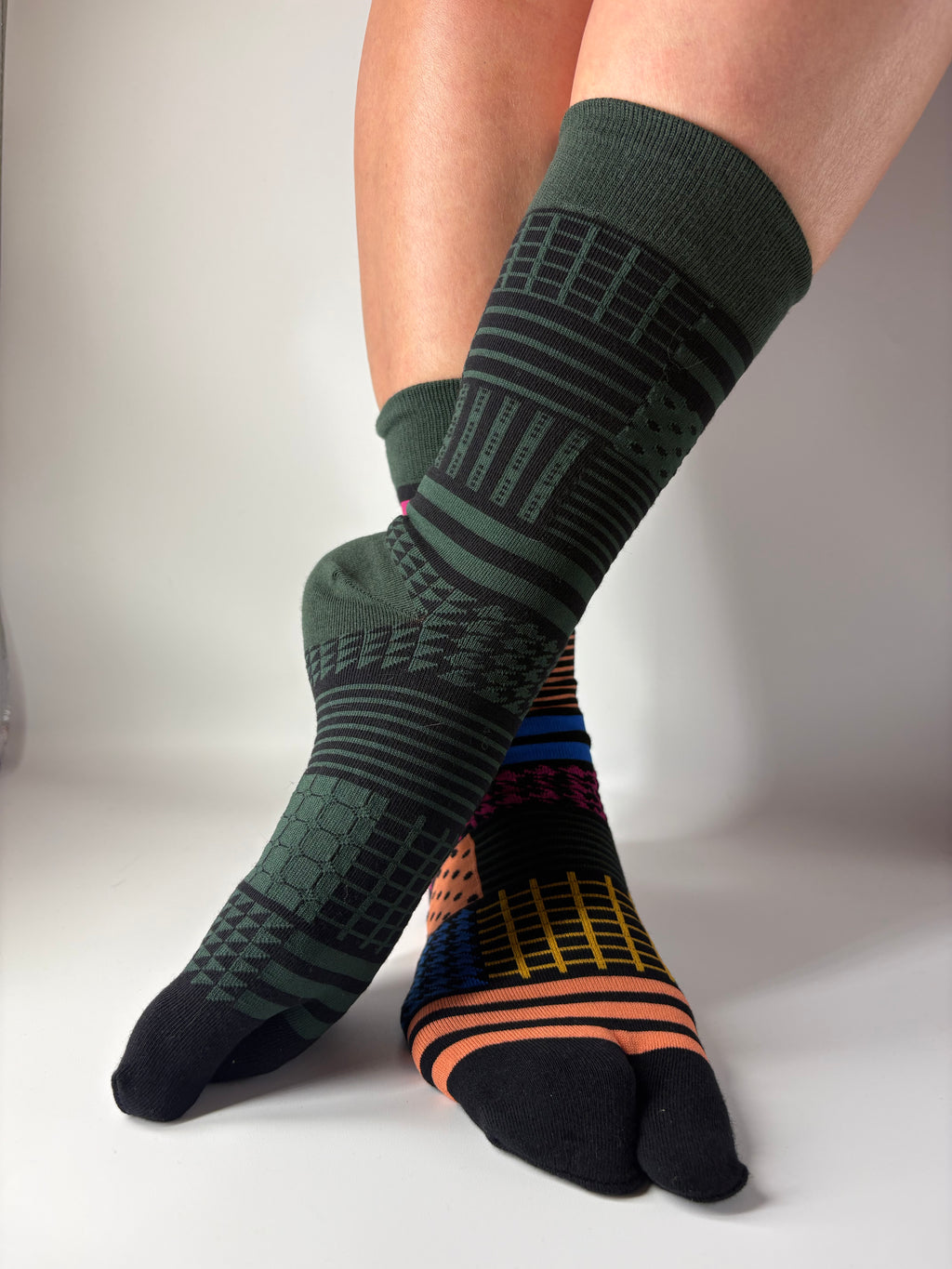 Person wearing green and black patterned socks on a white background