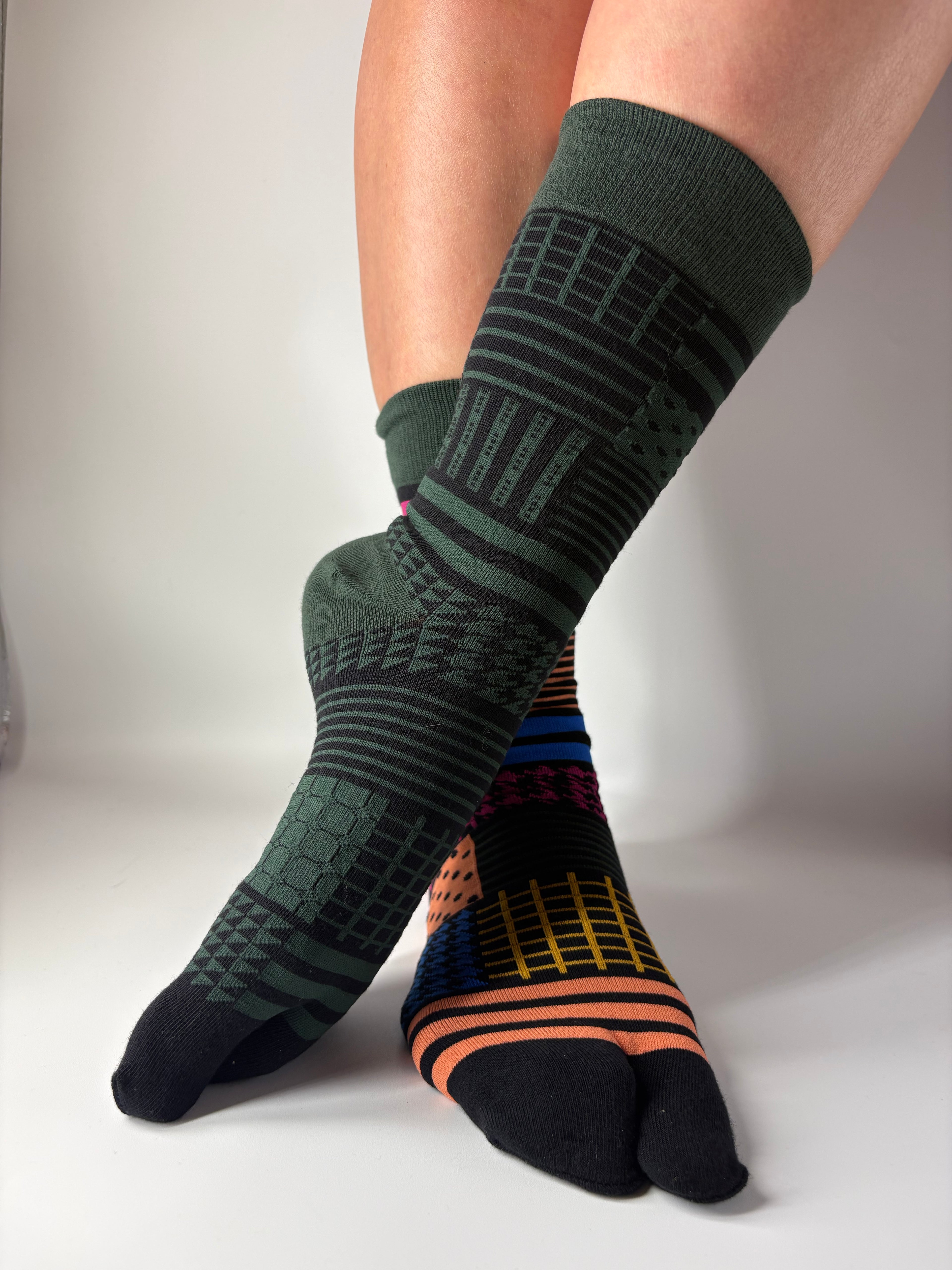 Person wearing green and black patterned socks on a white background