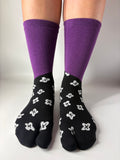 Purple socks with black and white floral pattern on a neutral background