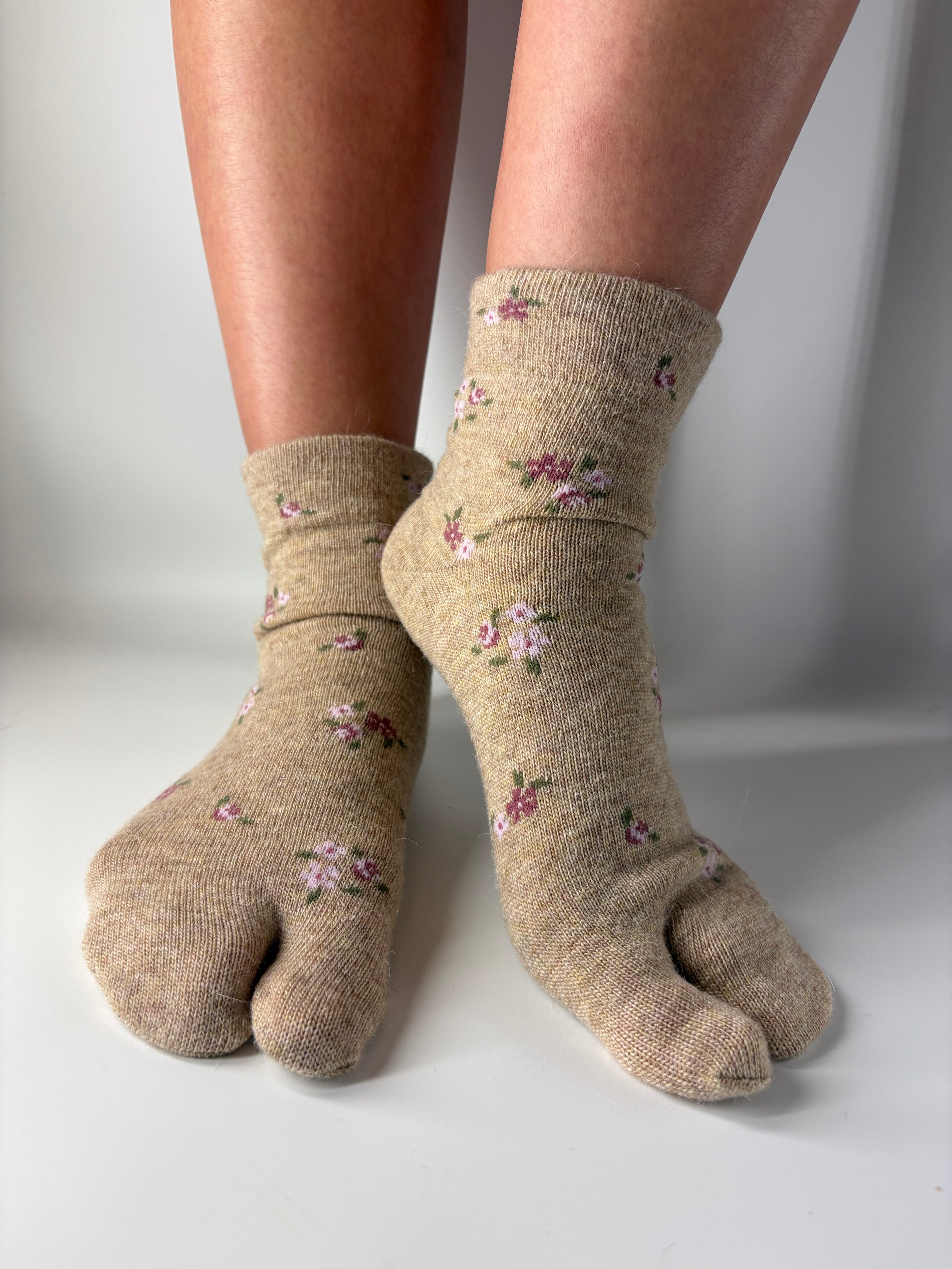 Beige socks with floral patterns worn by a person on a white background