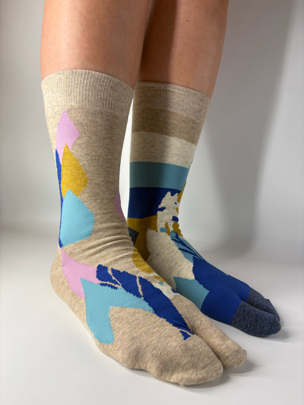 Colorful abstract patterned socks worn by a person on a white background