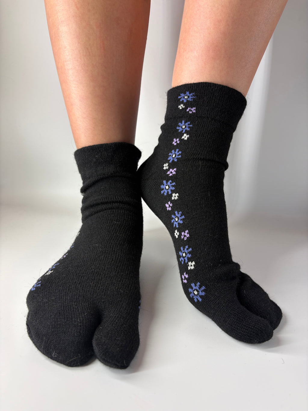 Black tabi socks with a blue and white floral pattern, shown on feet against a plain light background.