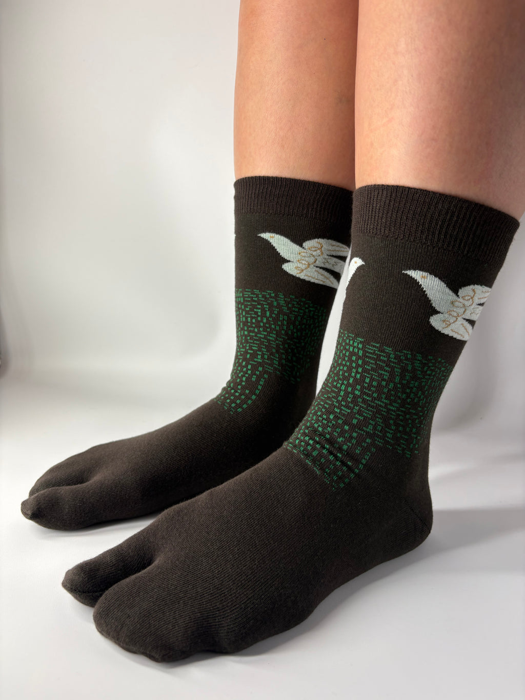 Tabi Co. brown split-toe cotton socks with a white dove and green speckled pattern, worn on feet