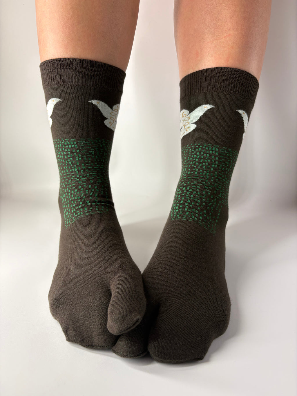 Tabi Co. brown split-toe cotton socks with a white dove and green speckled pattern, worn on feet