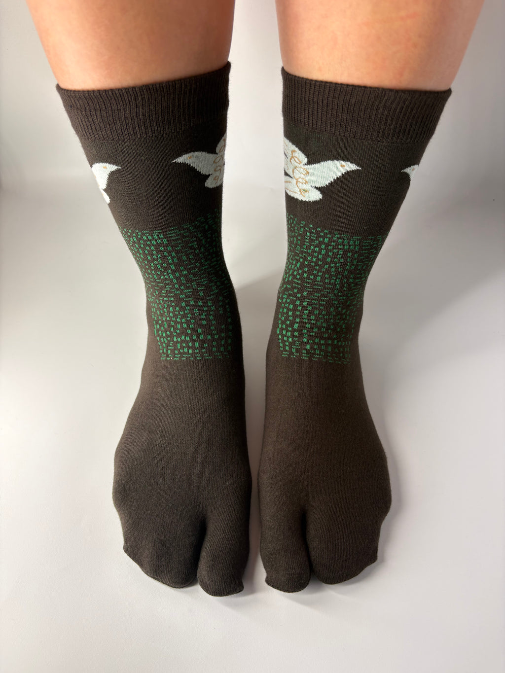 Tabi Co. brown split-toe cotton socks with a white dove and green speckled pattern, worn on feet