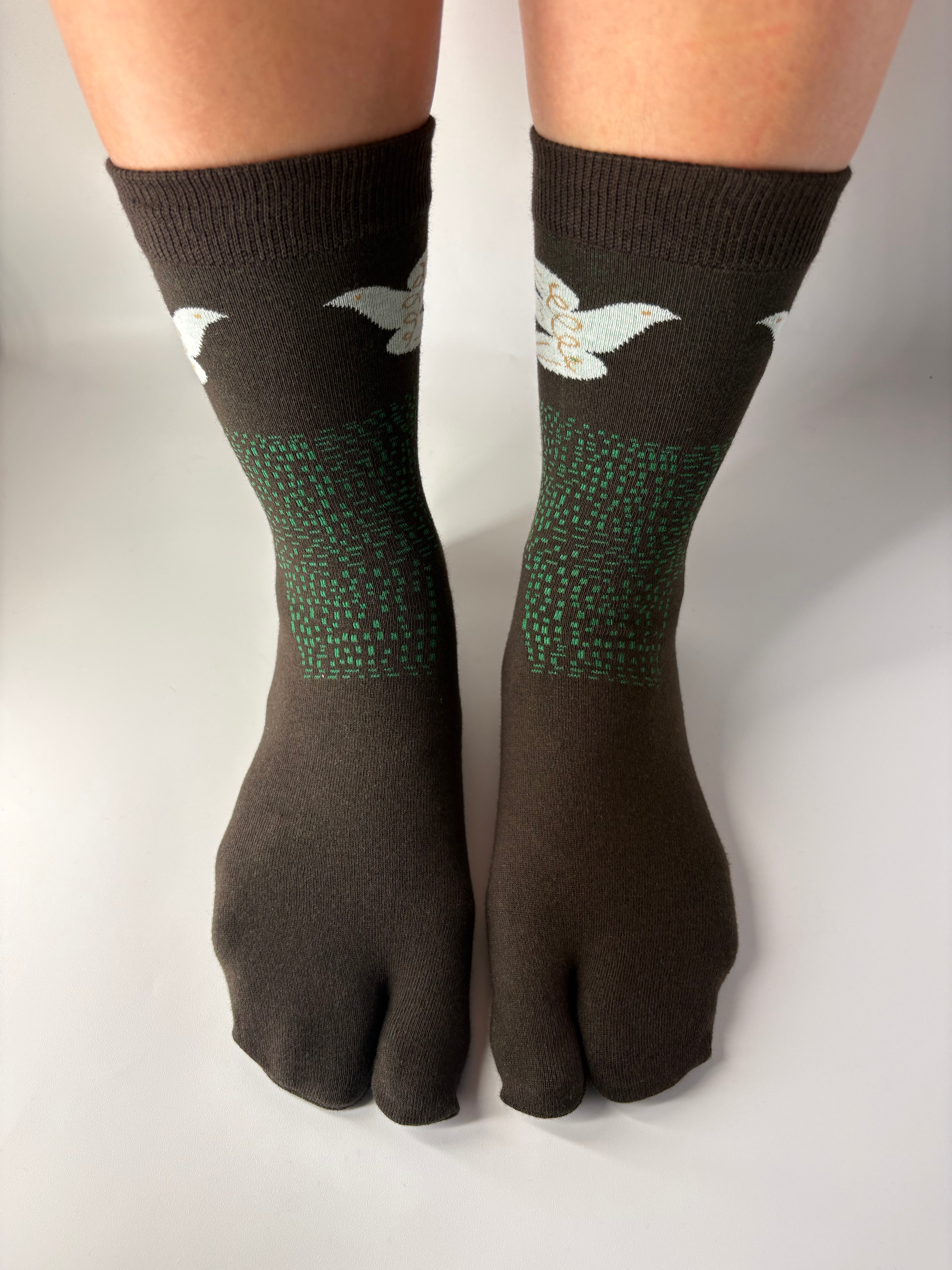 Tabi Co. brown split-toe cotton socks with a white dove and green speckled pattern, worn on feet