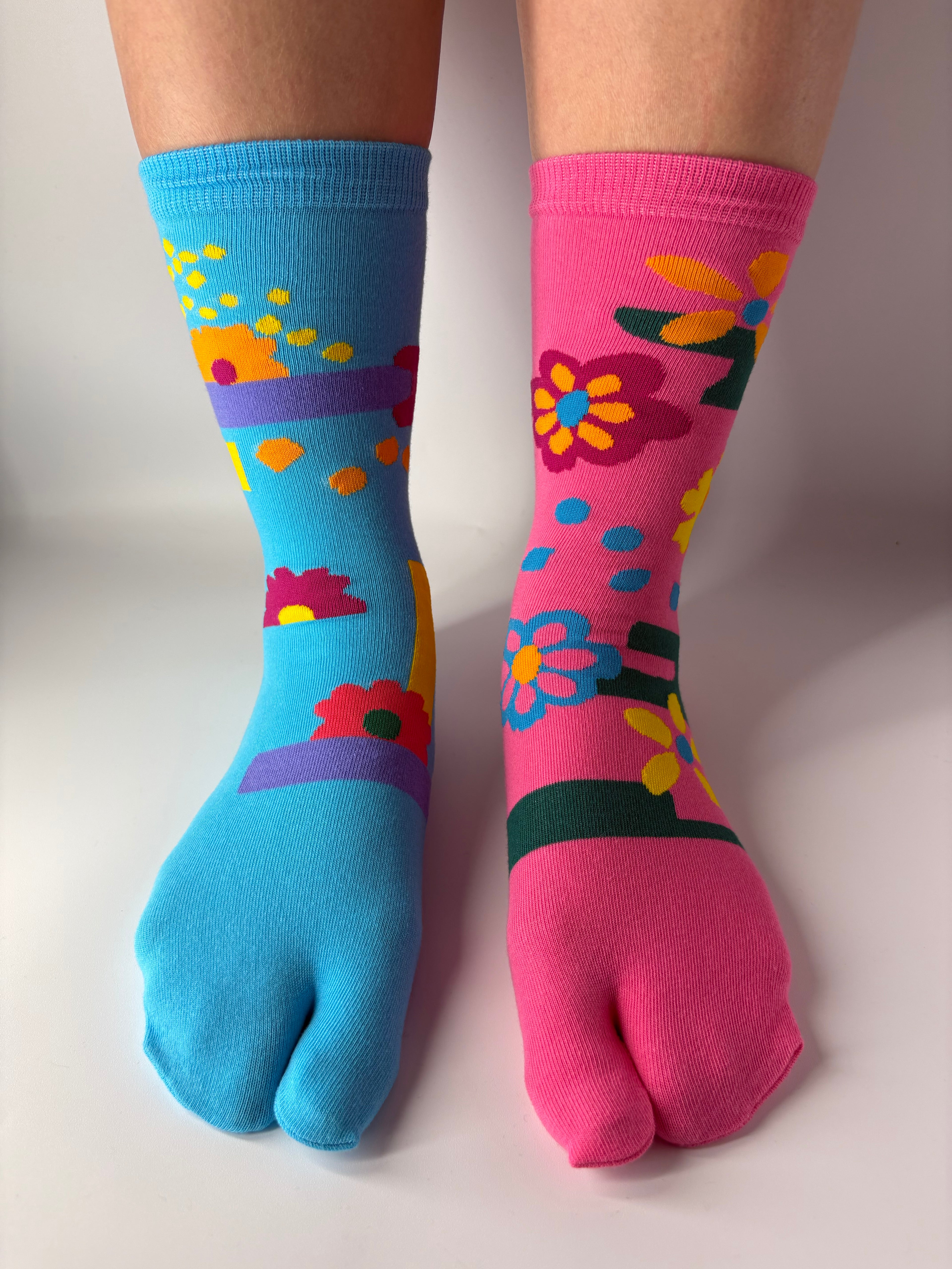 Tabi Co. split-toe cotton socks in sky blue and pink with a bright floral print, worn on feet