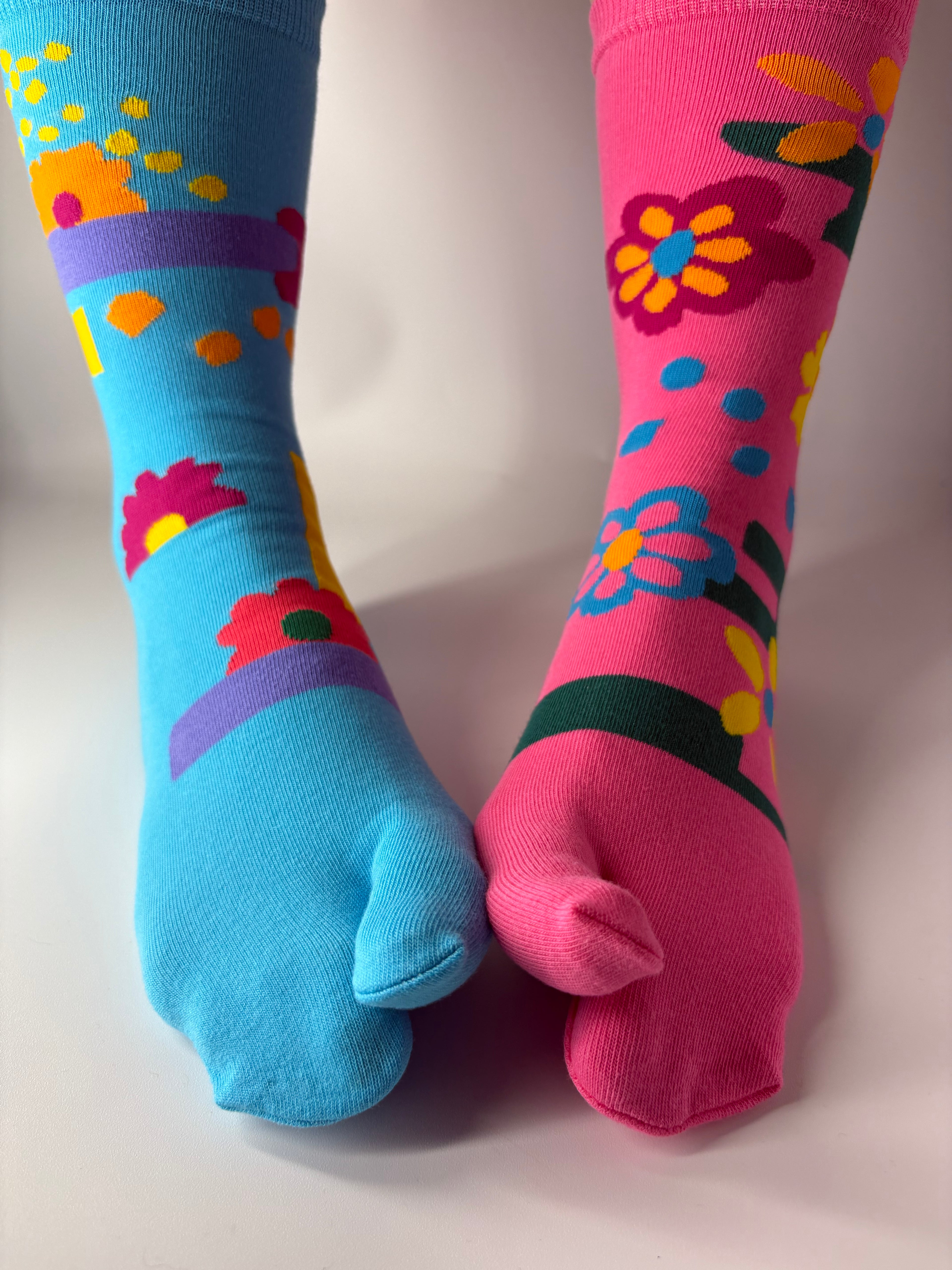 Tabi Co. split-toe cotton socks in sky blue and pink with a bright floral print, worn on feet